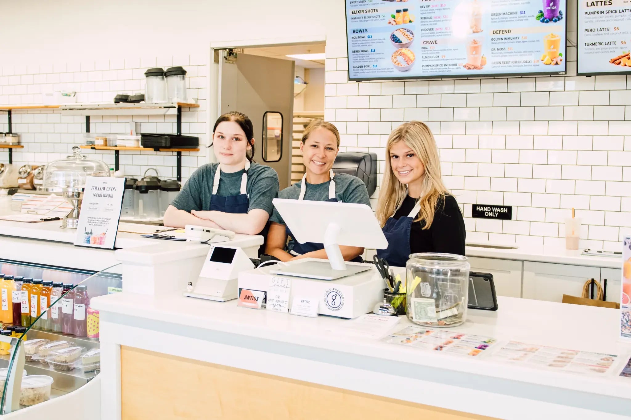 Three ANTIOX juice bar team members together behind the counter